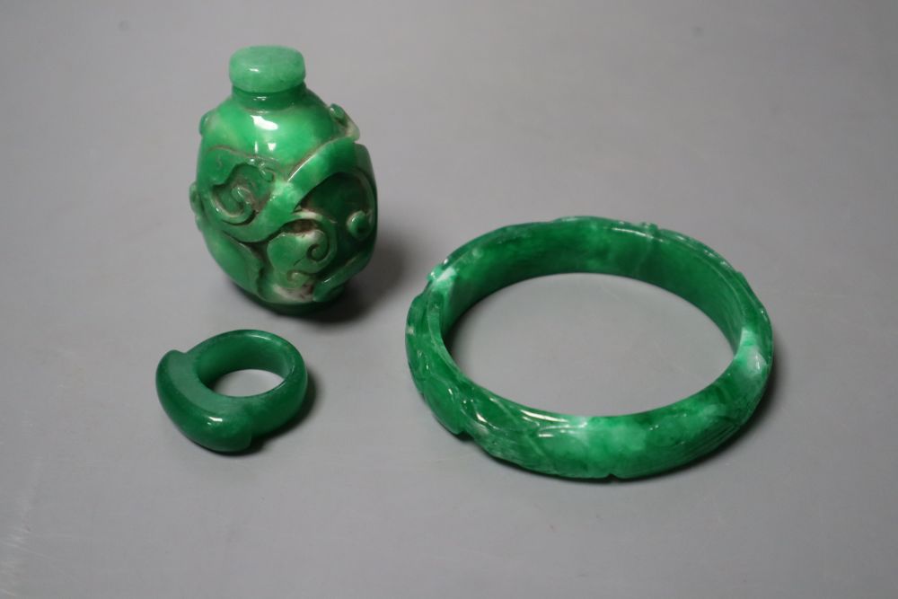 A Chinese green jadeite snuff bottle and stopper, a similar phoenix & dragon bangle and an archers ring